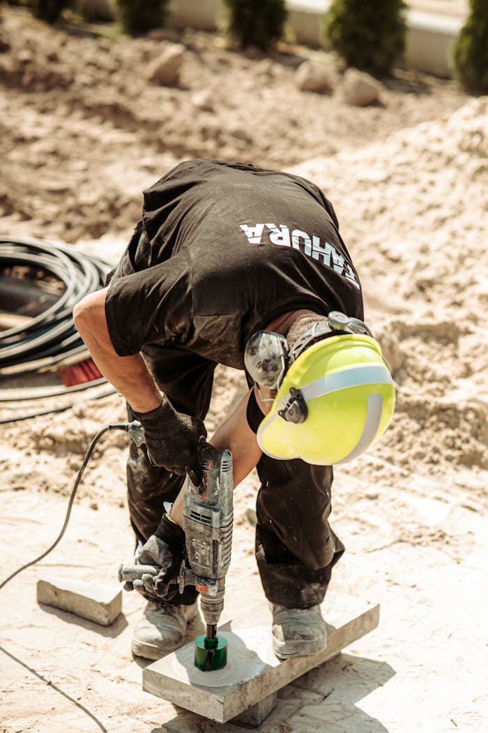 Worker operates a drill on a construction site in Grójec, Poland, showcasing industry.